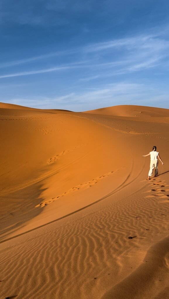 Walking in Sahara sand dunes in Morocco for Agafay vs Sahara Desert travel comparison