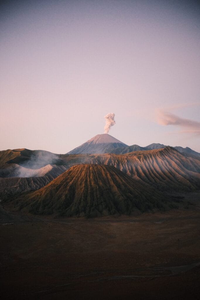 Pinkish glow of the sunrise hitting Mt Bromo after a sunrise hike in Indonesia